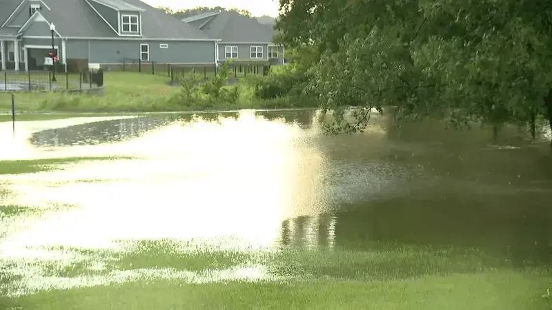 Floodwater spreading across a low yard below homes after heavy rain in Shelby County