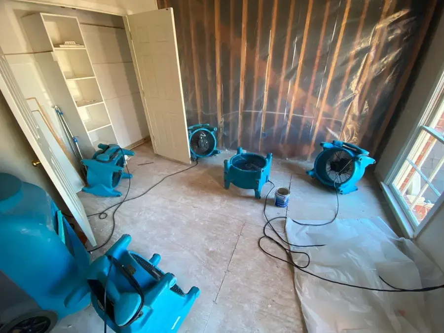 Air movers drying a stripped bedroom floor during a Cordova water damage job