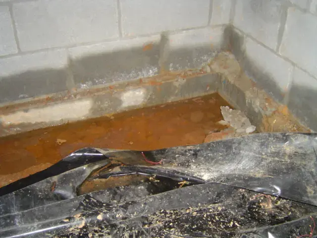 Standing water pooled on a torn vapor barrier in a Cordova crawl space