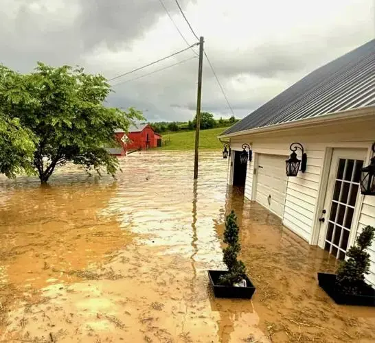 Muddy floodwater surrounding a home after creek flooding near Cordova